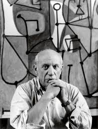 художник Пабло Пикассо на фоне своих картин в мастерской